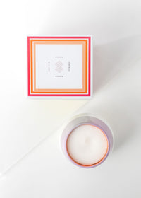 A book titled "Women" with a minimalistic cover design next to a Margot Elena Infinite She Find Your Fire Ceramic Candle on a white surface, viewed from above.