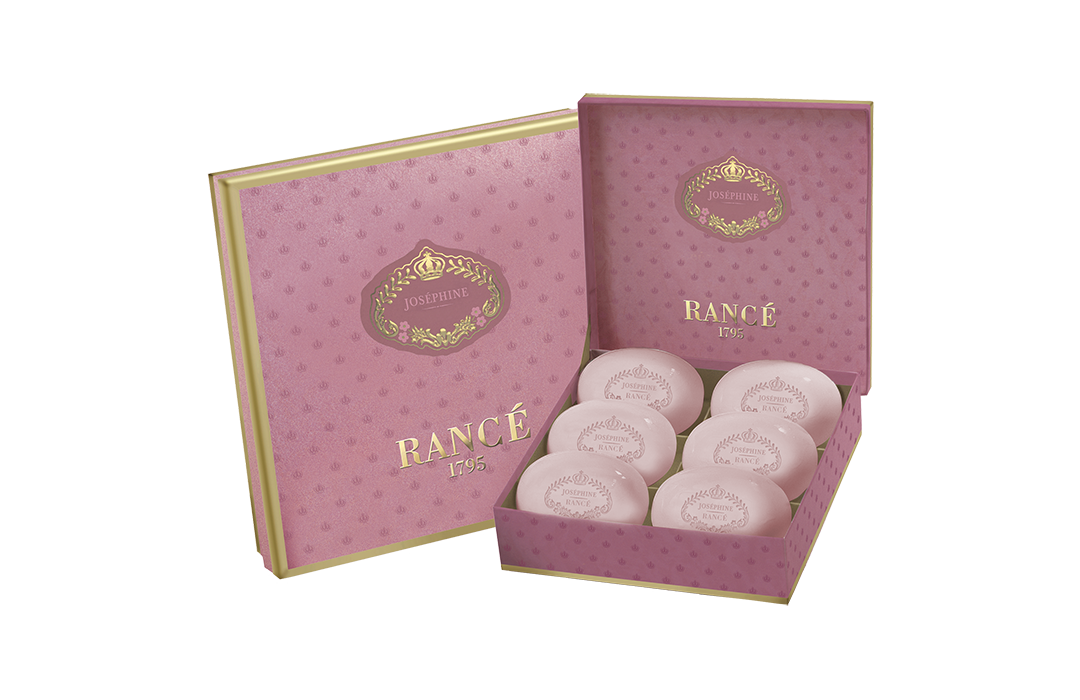 An elegant pink gift box containing six spherical, individually wrapped soaps scented with Rance Josephine fragrance, each labeled "Rancé" in decorative font, placed in an open pink box with a similarly designed.