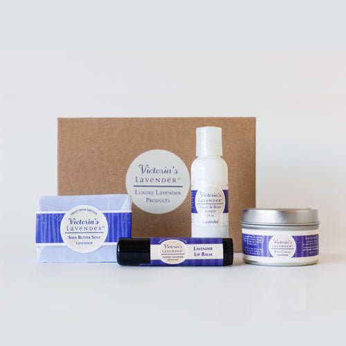 A set of Victoria's Lavender - Lavender Moisturizing Body Care Gift Set by Victoria's Lavender, including handmade soap, moisturizing lotion, balm, and a roll-on, displayed against a white background with a brown box.
