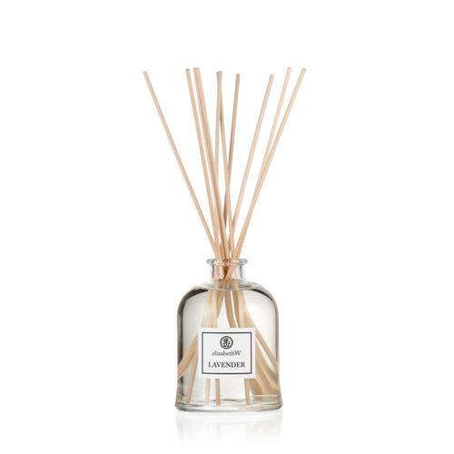 A Elizabeth W Purely Essential Lavender Diffuser with several sticks protruding from a clear glass bottle, isolated on a white background. This environmentally friendly home fragrance offers a natural aroma that enhances any space.