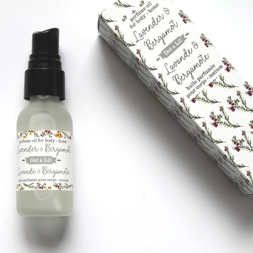 A bottle of Dot & Lil Lavender + Bergamot Perfume Oil with a spray nozzle next to its floral-patterned Dot & Lil Lavender & Hibiscus packaging box, placed on a white background.