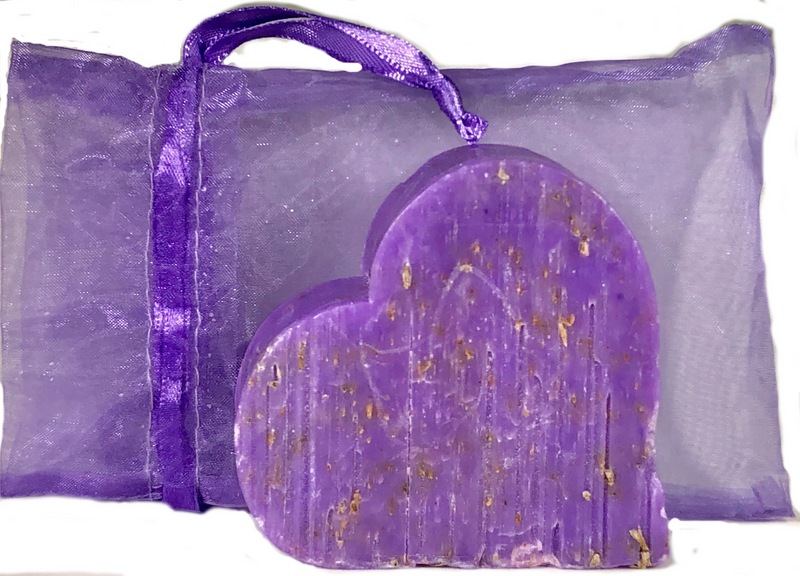 A purple, translucent organza bag with a drawstring, containing a Massalia Heart Soap - Lavender Exfoliating speckled with gold. The bag rests on a flat surface. (Made in Provence)