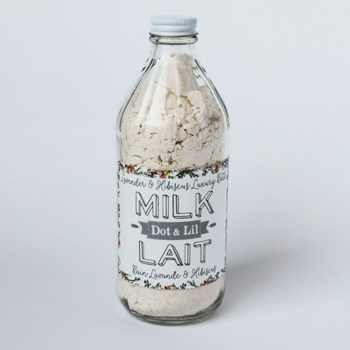 A vintage-style milk bottle containing Dot & Lil Lavender & Hibiscus Milk Bath, designed to offer a Cleopatra-like bathing experience, displayed