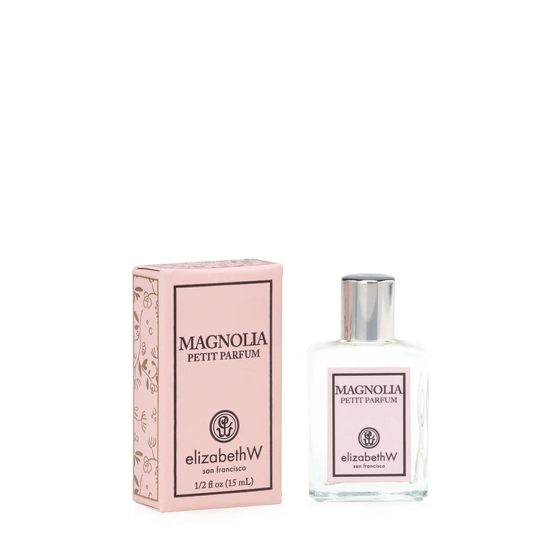 A bottle of Elizabeth W Signature Magnolia Eau de Parfum-Petit next to its pink packaging box. Both items feature elegant labels and designs.