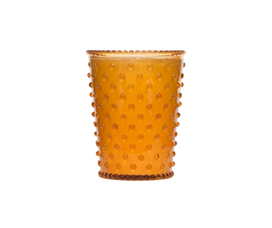 A textured amber glass tumbler with a dotted pattern all around, displayed against a plain white background, ideal for holding a Simpatico NO. 28 Pumpkin & Clove Hobnail Glass Candle.