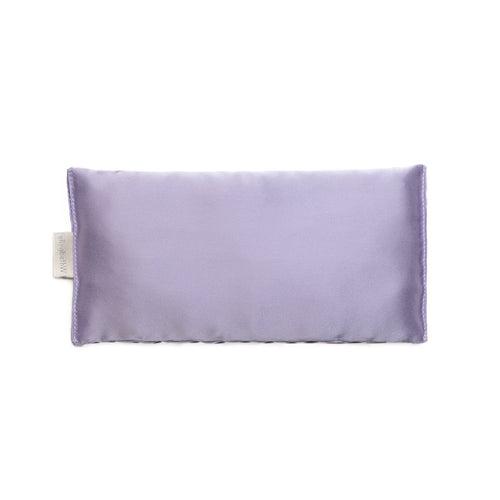 A purple-colored Elizabeth W Silk Eye Pillow infused with lavender, featuring a smooth texture and a visible tag, displayed against a plain white background.