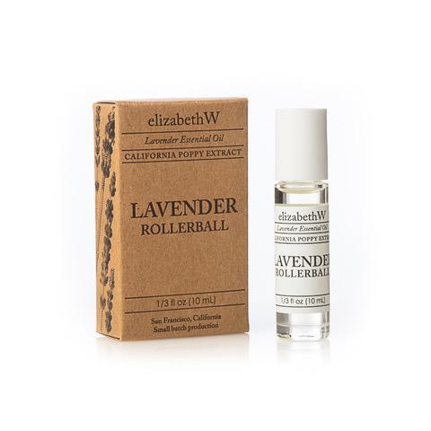 A product image of "elizabeth W Purely Essential Lavender Perfume Oil Rollerball" essential oil, featuring a small brown cardboard box labeled next to a clear glass rollerball bottle with the same branding and showcasing its calming scent.