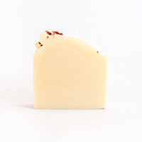 A bar of SOAK Bath Co. - Rose Petal Soap, with dried rose petals, wrapped in biodegradable seed paper, against a plain white background.