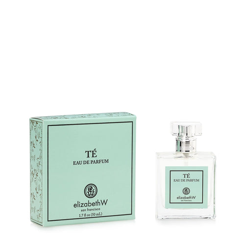 A clear glass perfume bottle labeled "elizabeth W Signature Té Eau de Parfum" next to its matching green box with Amalfi lemons prints, both placed on a white background.