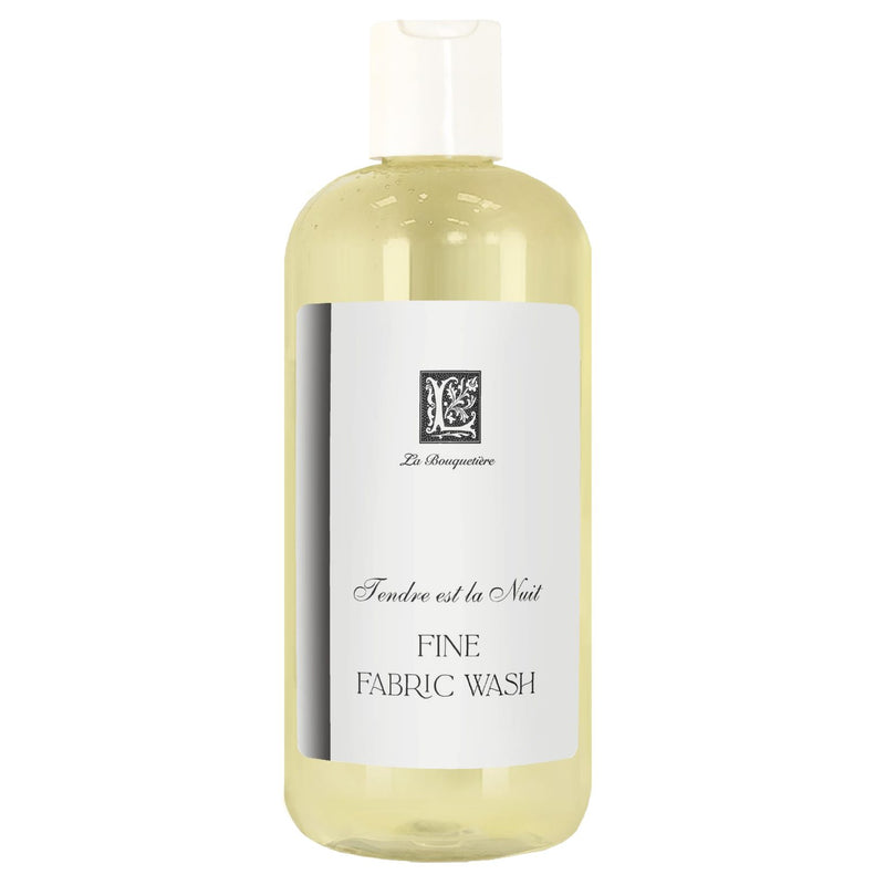A clear plastic bottle of La Bouquetiere Tendre est la Nuit Fine Fabric Wash for fine fabric wash with a simple, elegant label featuring black and white text and a decorative monogram. The label says "fine fabric wash - tend