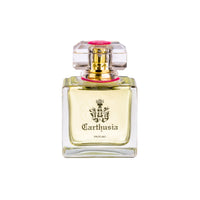 A clear glass perfume bottle with a royal crest labeled "Carthusia I Profumi de Capri." The bottle has a square base, translucent yellow liquid inside, and a pink cap with a faceted top that hints