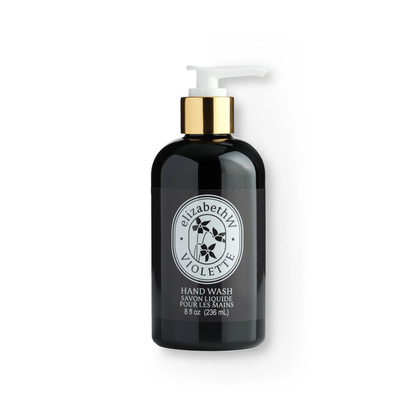 A black bottle of elizabeth W Atelier Violette Hand Wash with a white and black label and a gold pump, isolated on a white background.