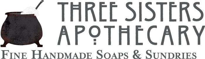 A logo featuring a black cauldron filled with white soap bubbles on the left, and text on the right reading "Three Sisters Apothecary, Fine Handmade Soaps & Sundries" in a rustic font.