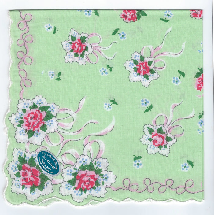 A vintage green handkerchief featuring a floral pattern with pink roses, white lace-like trim, and scalloped edges. Small blue flowers and swirls accent the design. A sticker is on the lower left corner.