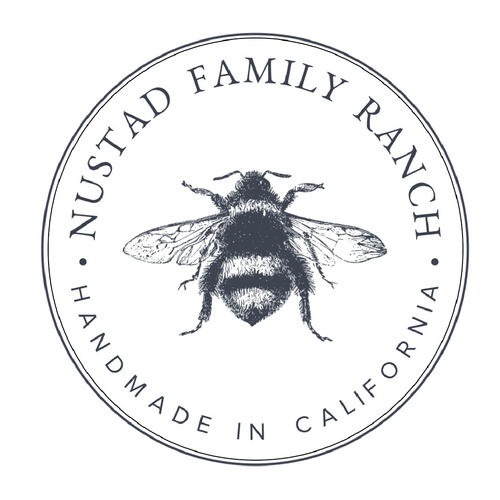 Circular logo of Nustad Family Ranch featuring a detailed illustration of a bee at the center, encircled by text "Nustad Family Ranch" and "Handmade in California.