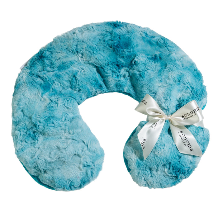 A white U-shaped pillow with intricate blue geometric and floral patterns. A ribbon with "Sonoma" printed on it is tied around one arm of the pillow.