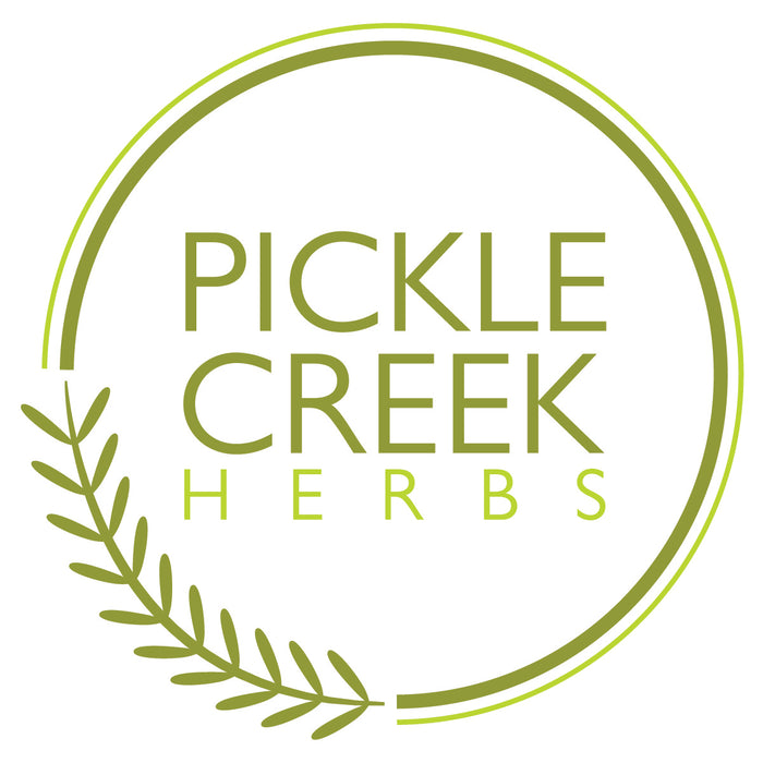 Logo of Pickle Creek Herbs featuring the name in green capital letters, encircled by a partial green circle with a sprig of leaves extending from the lower left.