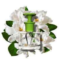 A clear 60ml Caswell Massey Gardenia Eau de Toilette bottle with a green cap, set before white gardenias and green leaves, evokes this elegant floral fragrance with subtle white woods undertones.