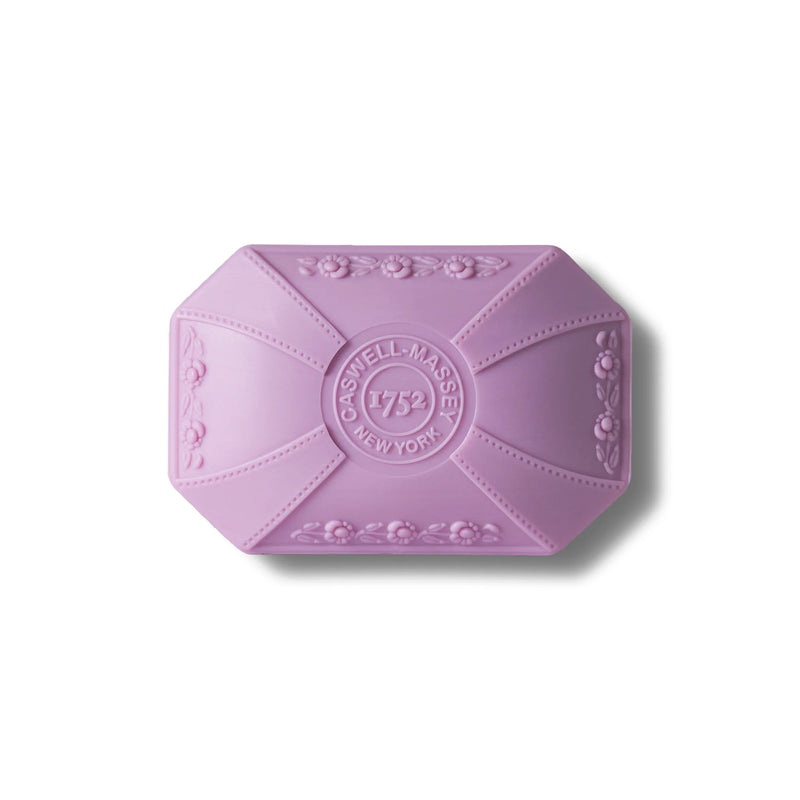 A Caswell-Massey Lilac Luxury Bar Soap with ornate floral embossing and the text "Caswell-Massey 1752 New York" featured prominently in a vintage design, presented against a white background.