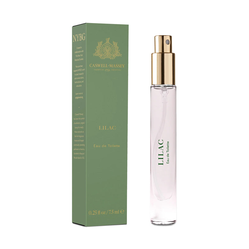 A bottle of Caswell Massey Lilac eau de toilette - 7.5ml beside its green box with gold accents, detailing a list of ingredients on the side. The bottle has a clear body.