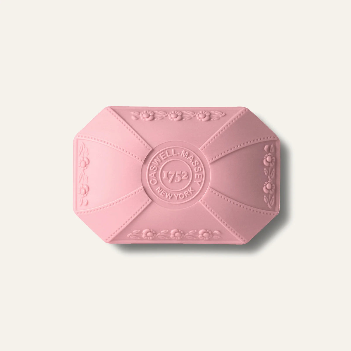 Caswell-Massey Rose Luxury Bar Soap 100g is a pink, rectangular soap with beveled corners and embossed patterns, featuring a central “CASWELL-MASSEY 1752 NEW YORK” emblem—cruelty-free for an elegant cleansing experience.
