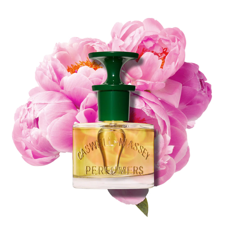 A perfume bottle with a green cap, surrounded by vibrant pink peonies, isolated on a white background. The bottle label reads "Caswell Massey Peony Perfume 60ml".