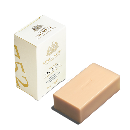 The Caswell-Massey Oatmeal Bar Soap, a moisturizing beige bar, is shown beside its cream-colored box with gold accents and the Caswell-Massey name. The elegant packaging highlights the soap's luxury.