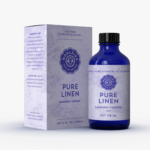 A Woolzies Pure Linen Essential Oil blue glass bottle sits next to its white and blue box, both featuring the Woolzies logo—ideal for freshening fabrics or scenting dryer balls naturally.