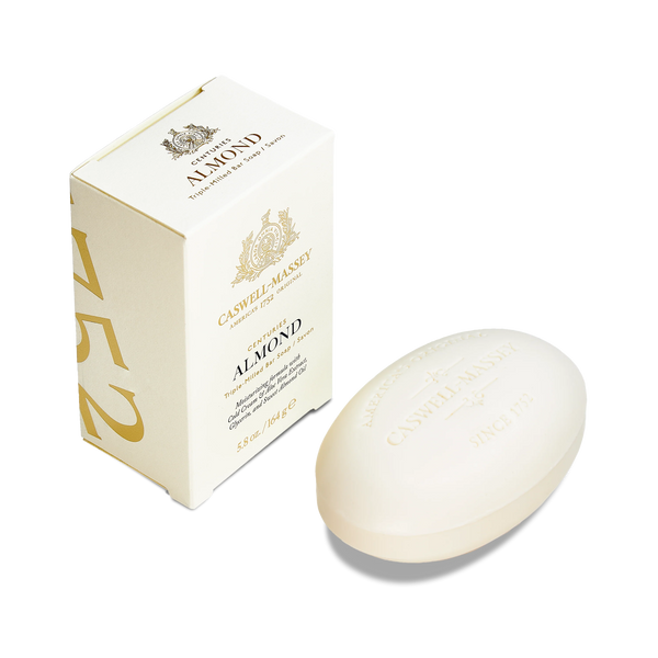 A Caswell-Massey Almond Bar Soap, oval and embossed with the brand name and "Since 1752", sits by its cream box adorned with gold text and the number 1752 on the side.