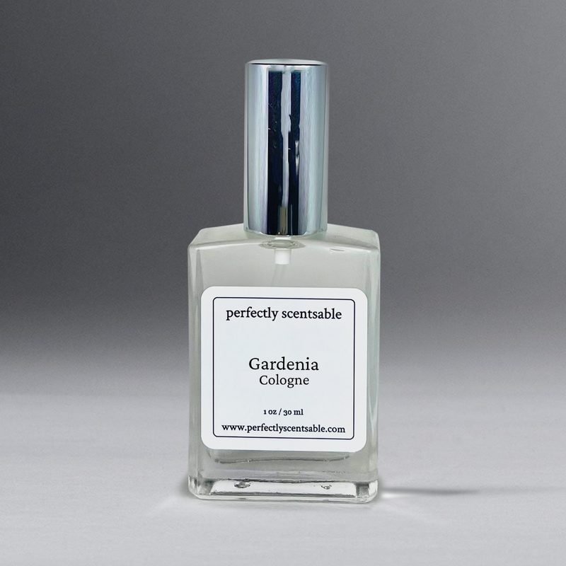 A clear rectangular glass bottle of Perfectly Scentsable Gardenia Perfume Oil - 1oz Cologne Spray, boasting a long-lasting aroma and a shiny silver cap. The white label reads "perfectly scentsable," "Gardenia Perfume Oil," with the volume "1 oz / 30 ml," and the website "www.perfectlyscentsable.com." The background transitions from dark gray to light gray.