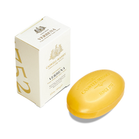 A yellow oval Caswell-Massey Verbena Bar Soap with plant-based glycerin sits beside its cream-colored box, adorned with gold text and decorative accents.