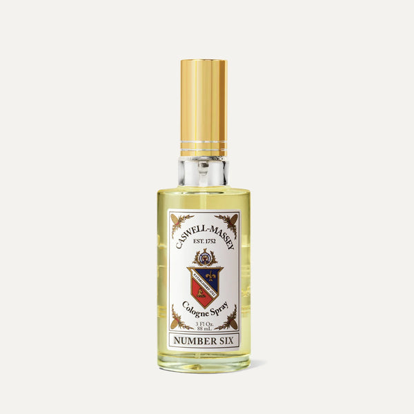 The Caswell-Massey Number Six Cologne features a clear glass bottle with a gold cap and decorative label, containing yellow liquid and offering the classic citrus woody scent from Caswell-Massey.