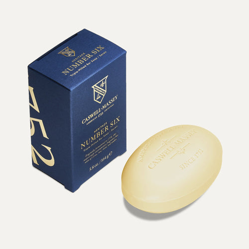 A blue box labeled "Caswell Massey Number Six Bar Soap Set" sits next to an oval, beige triple-milled soap bar embossed with the Caswell Massey branding and logo.