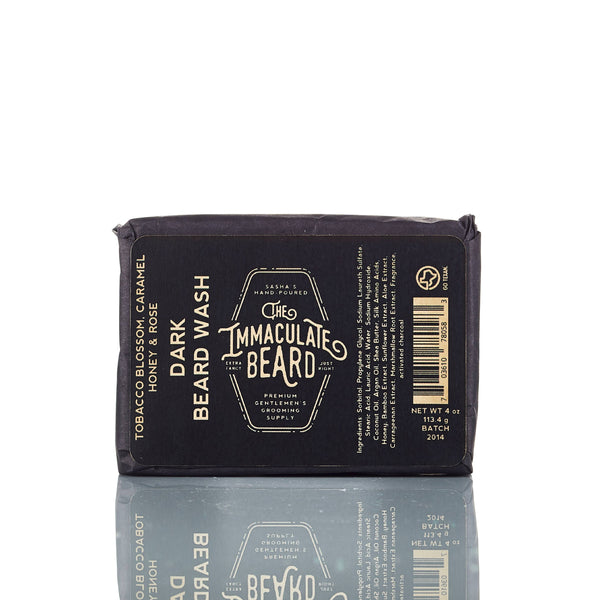 A bottle of The Immaculate Beard DARK Cologne Oil by The Immaculate Beard, featuring notes of tobacco blossom, caramel, honey, and rose for a long-lasting men's fragrance in sleek black packaging.