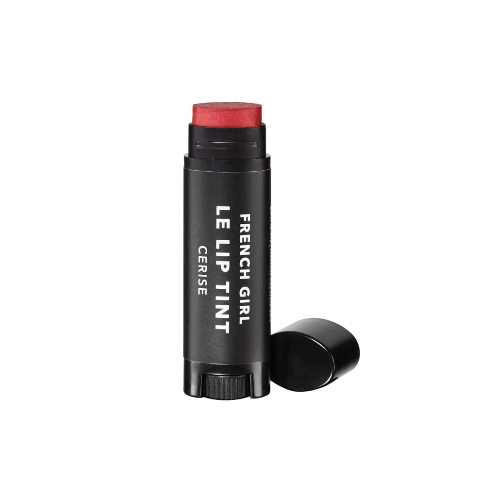 A tube of FRENCH GIRL - Tinted Lip Balm | Cerise stands upright with the cap off, showcasing the hydrating vegan formula. The sleek black tube with white text is set against a clean white background.