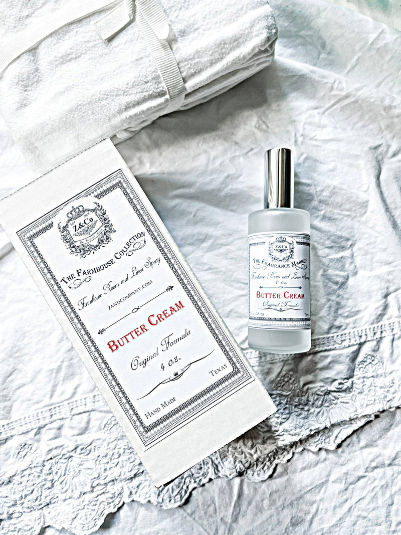A bottle of Z&Co. Salt Farmhouse Room/Linen Spray by Z&Co. and its box sit on white, textured linens beside a folded towel, creating a clean, bright, and elegant display.