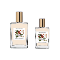 Two glass bottles with gold caps, labeled "FRENCH GIRL Eau Du Tabac Organic Vegan Natural Aromatherapy Perfume," feature floral and leaf designs. These vegan, alcohol-free perfumes from FRENCH GIRL come in two sizes.