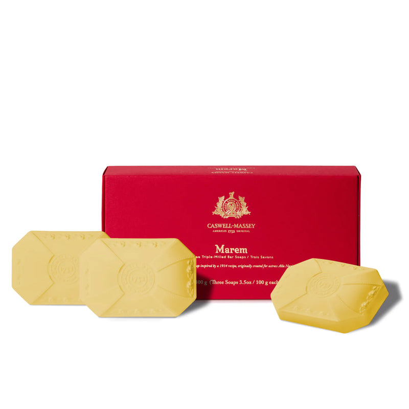 A red rectangular box labeled "Caswell Massey" with three yellow, oval-shaped Caswell Massey Marem soaps, each embossed with the company logo, displayed in front of the box.