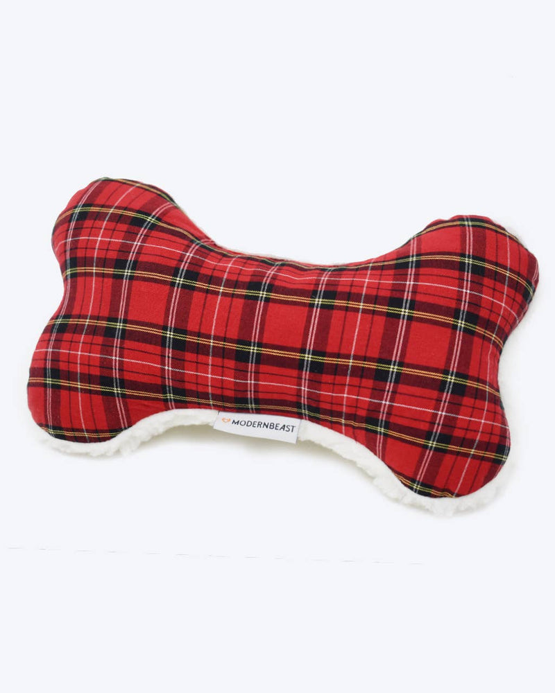 The MODERNBEAST Modernbeast Holiday Lavender Zenbone is a bone-shaped dog toy in red tartan plaid with white fuzzy edging, infused with organic lavender for calm, displayed on a plain white background.