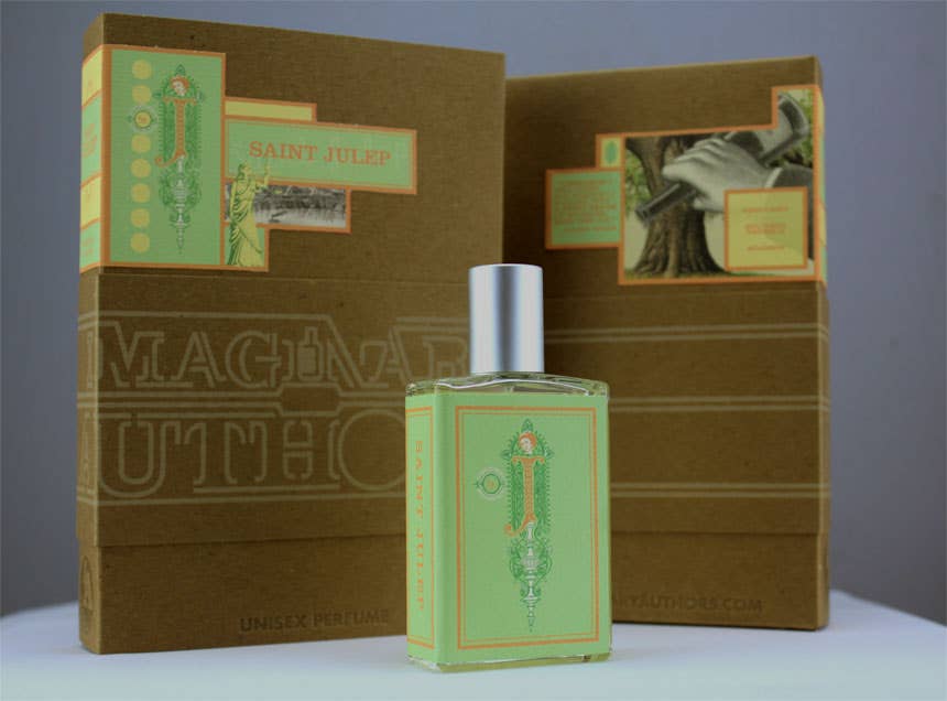 A bottle of Imaginary Authors Saint Julep - Large Size unisex perfume stands in front of its box. Both the bottle and box showcase light green and peach label designs adorned with intricate detailing and text, evoking notes of sweet mint. The plain background highlights the beautiful packaging by Imaginary Authors.