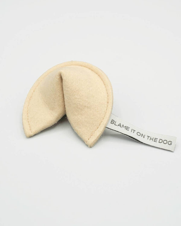 The MODERNBEAST Kitty Fortune Cookie Organic Catnip Cat Toy is an eco felt cat toy shaped like a fortune cookie with a “BLAME IT ON THE DOG” fabric tag, filled with organic catnip, shown on a plain white background.