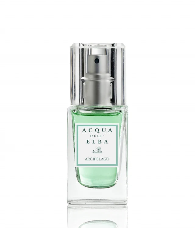 A travel-size 15ml Acqua dell'Elba Arcipelago Uomo EdP features a clear glass bottle with a metallic spray top and green liquid set on a white background. The label showcases the brand and scent name in green and black, inspired by the aromatic essence of the Tuscan Archipelago.