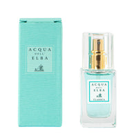 A bottle of Acqua dell'Elba Classic Donna Eau de Parfum Travel Size 15ml is placed next to its corresponding teal box. The bottle features a golden spray top and holds a clear, light turquoise liquid. Both the box and the bottle are adorned with minimalist designs and elegant labels.