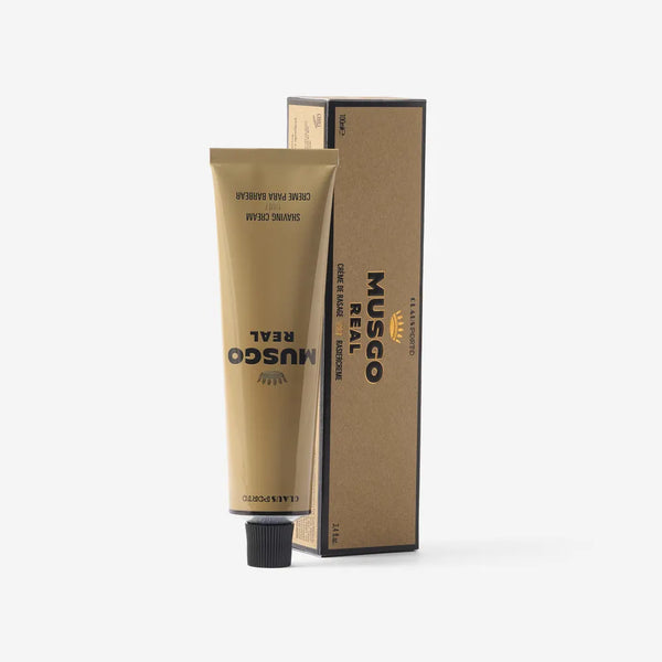 A gold tube of Claus Porto Musgo Real 1887 Shave Cream stands upright beside its matching brown and black box on a white background, capturing the vintage charm of this Claus Porto 1887 classic.