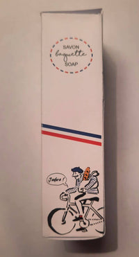 A white Senteurs De France soap box labeled "The 'Baguette' Soap" features a cartoon man in a beret riding a bike with a baguette, saying "J'adore!" under blue, white, and red stripes—a playful French keepsake.