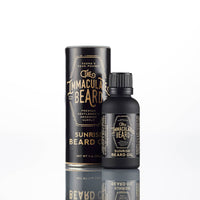 A bottle of The Immaculate Beard SUNRISE Beard Oil by The Immaculate Beard stands before its matching black cylindrical packaging with gold text, both displayed on a white background.