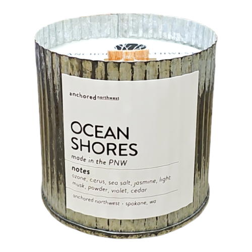 The Anchored Northwest Ocean Shores Rustic Vintage Farmhouse candle, made in Spokane, WA, features a wood wick and comes in a metal tin. Its scent blends ozone, citrus, sea salt, jasmine, musk, powder, violet, and cedar for a long-lasting burn.