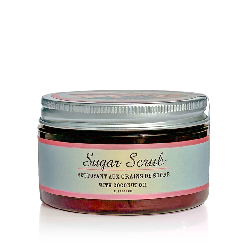 A container of handmade, cruelty-free scrub with coconut oil. The jar has a metallic screw-on lid and a label that reads, "Barefoot Venus Coconut Kiss Sugar Body Scrub." The product has a volume of 3.1 oz/90g. The paraben-free, sulfate-free packaging is light blue with a pink accent.