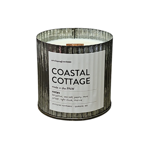 A large metallic Soy wax candle, the Anchored Northwest Coastal Cottage Rustic Vintage Wood Wick, features notes of bergamot, sea salt, peony, mint, juniper, light musk, and marine. A red triangle on the package reads "NEW SCENT.