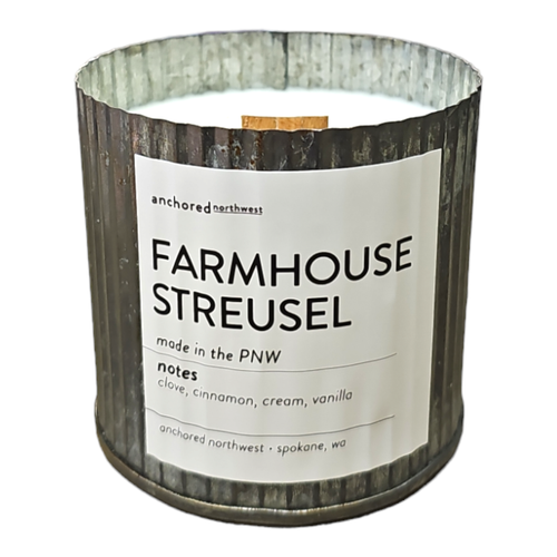 The Anchored Northwest Farmhouse Streusel Rustic Vintage Farmhouse Wood Wick Candle, handcrafted by Anchored Northwest in Spokane, WA, is a soy wax candle with fragrant notes of clove, cinnamon, cream, and vanilla. This metal container candle embodies a rustic vintage charm and represents the essence of the Pacific Northwest.